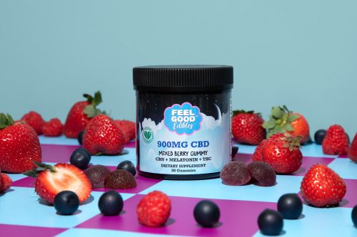 900MG CBD mixed berry gummy jar surrounded by strawberries and blueberries on a colorful background.