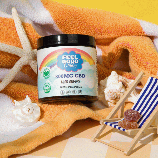 300mg CBD bear gummy container on a beach towel with seashells and a miniature chair.